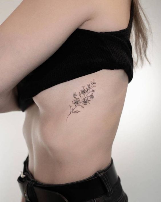 ramo de flores minimalista tatuado na costela 