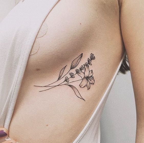 flor com ramo e folhas tatuado na costela 