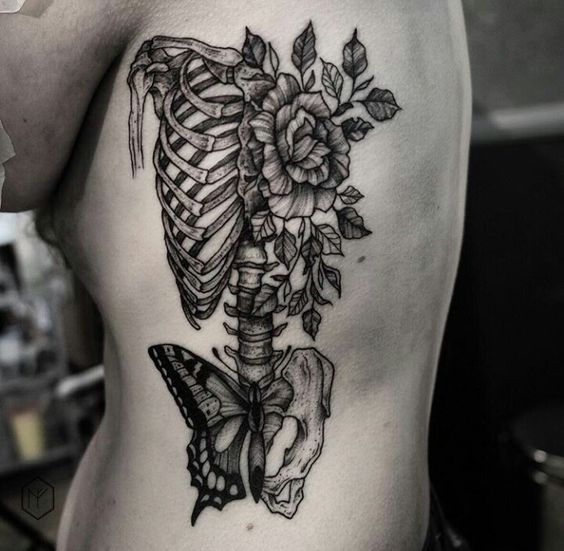 esqueleto com flores tatuado na costela