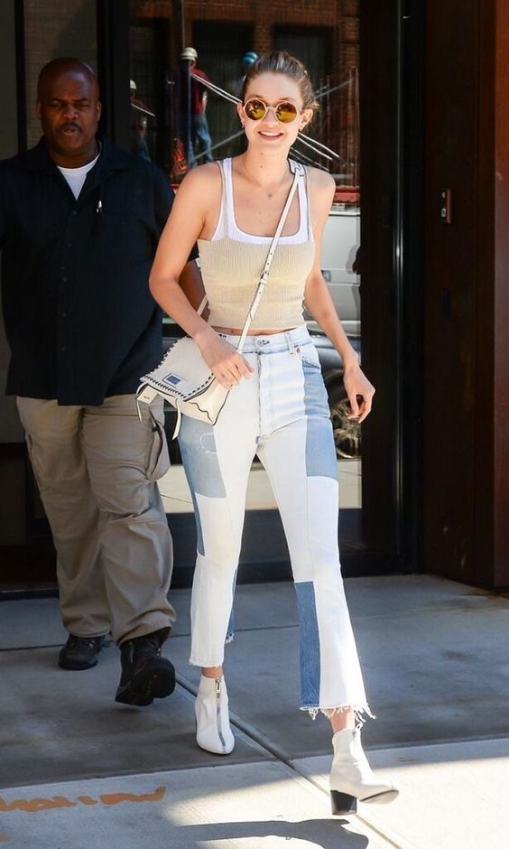 atriz usa calça jeans flare com botas brancas e regata cropped