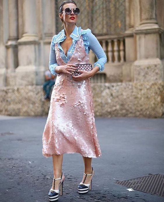 mulher andando pela cidade com blusa azul bebe e vestido rosa de paetê sobrepondo o look