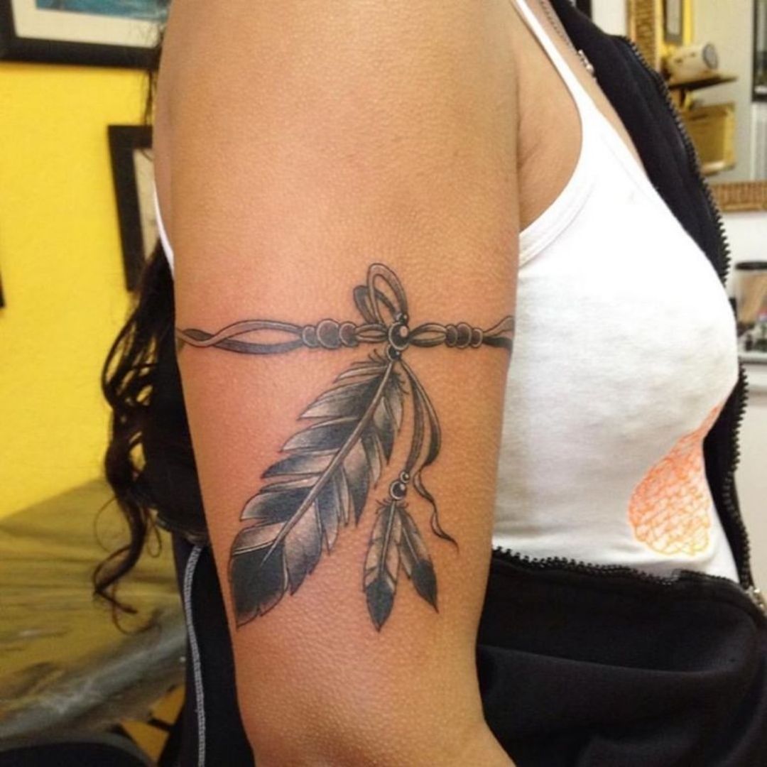 Tatuagem feminina no braço de penas