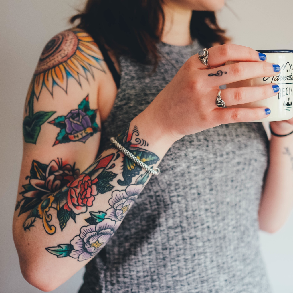 Mulher com braço tatuado segurando uma caneca