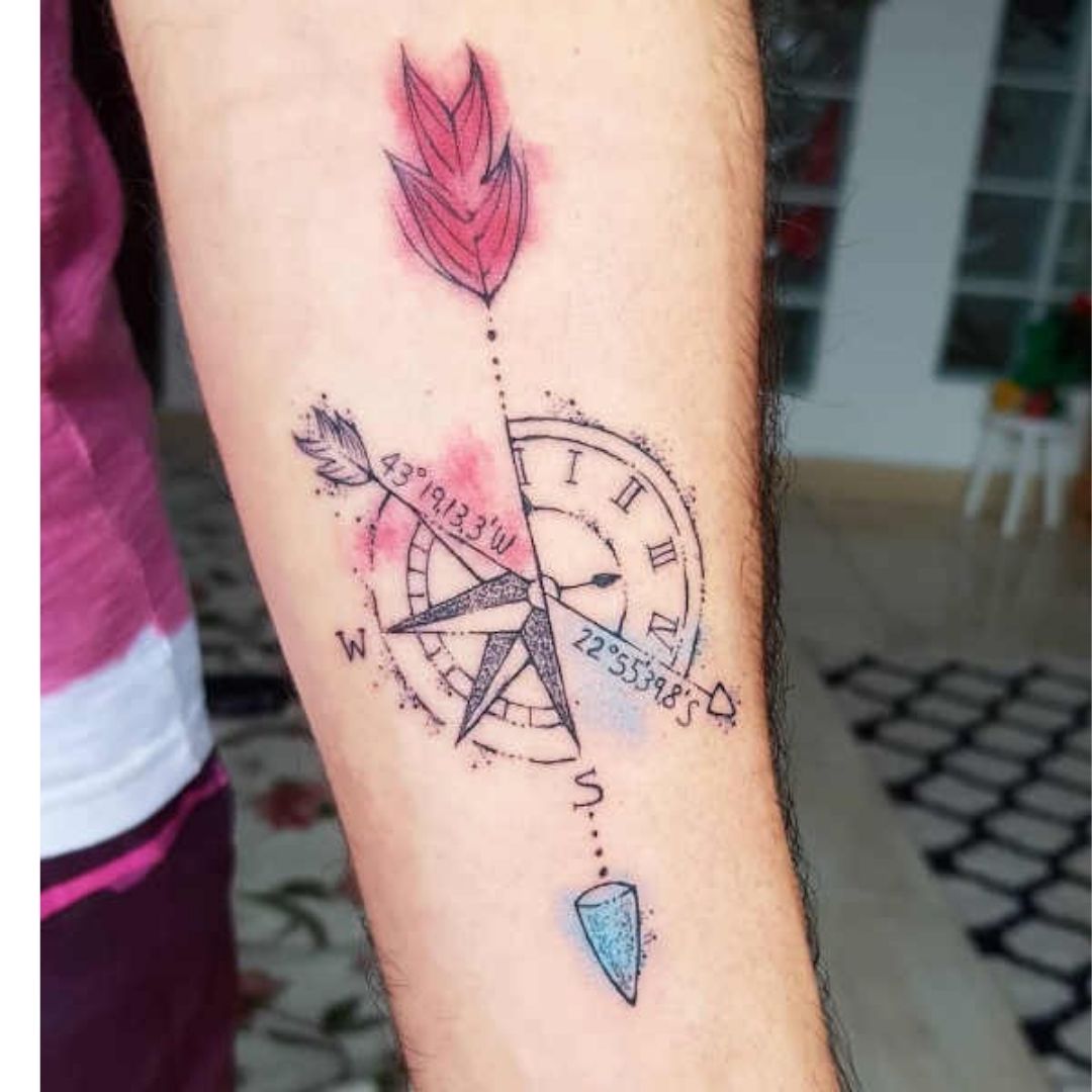 Tatuagem de uma bússola e uma pena o braço
