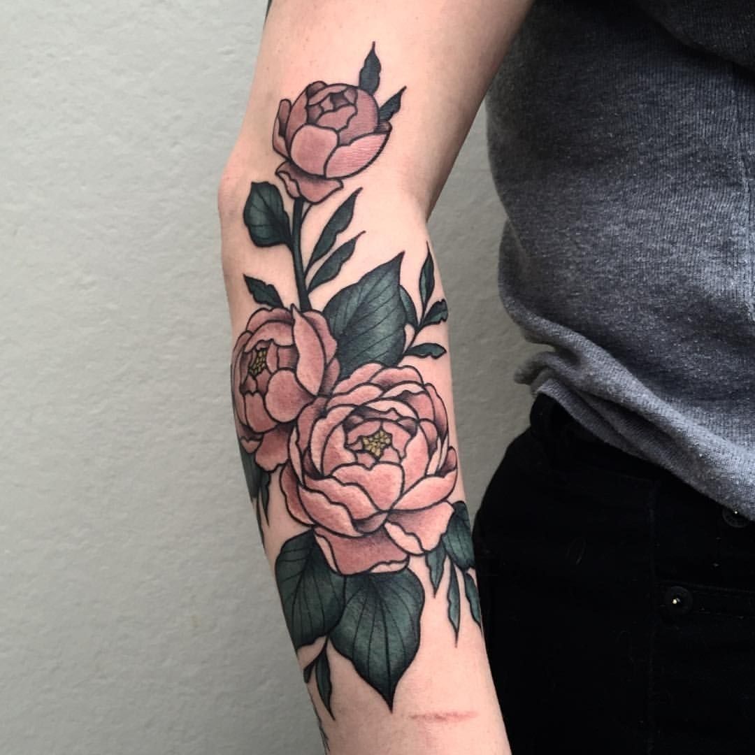 Tatuagem no braço perto do cotovelo com rosas e folhas coloridas 