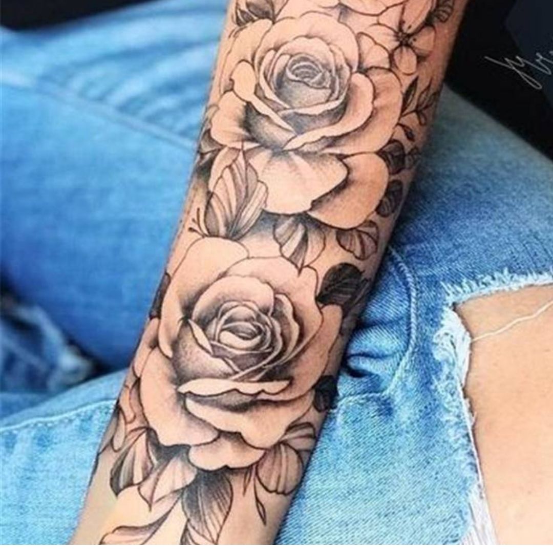 Tatuagem no antebraço com rosas e folhas.