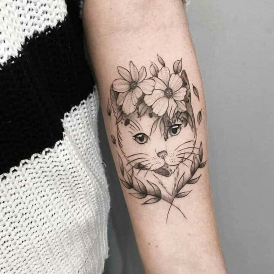 Tatuagem de um gato com flores e folhas