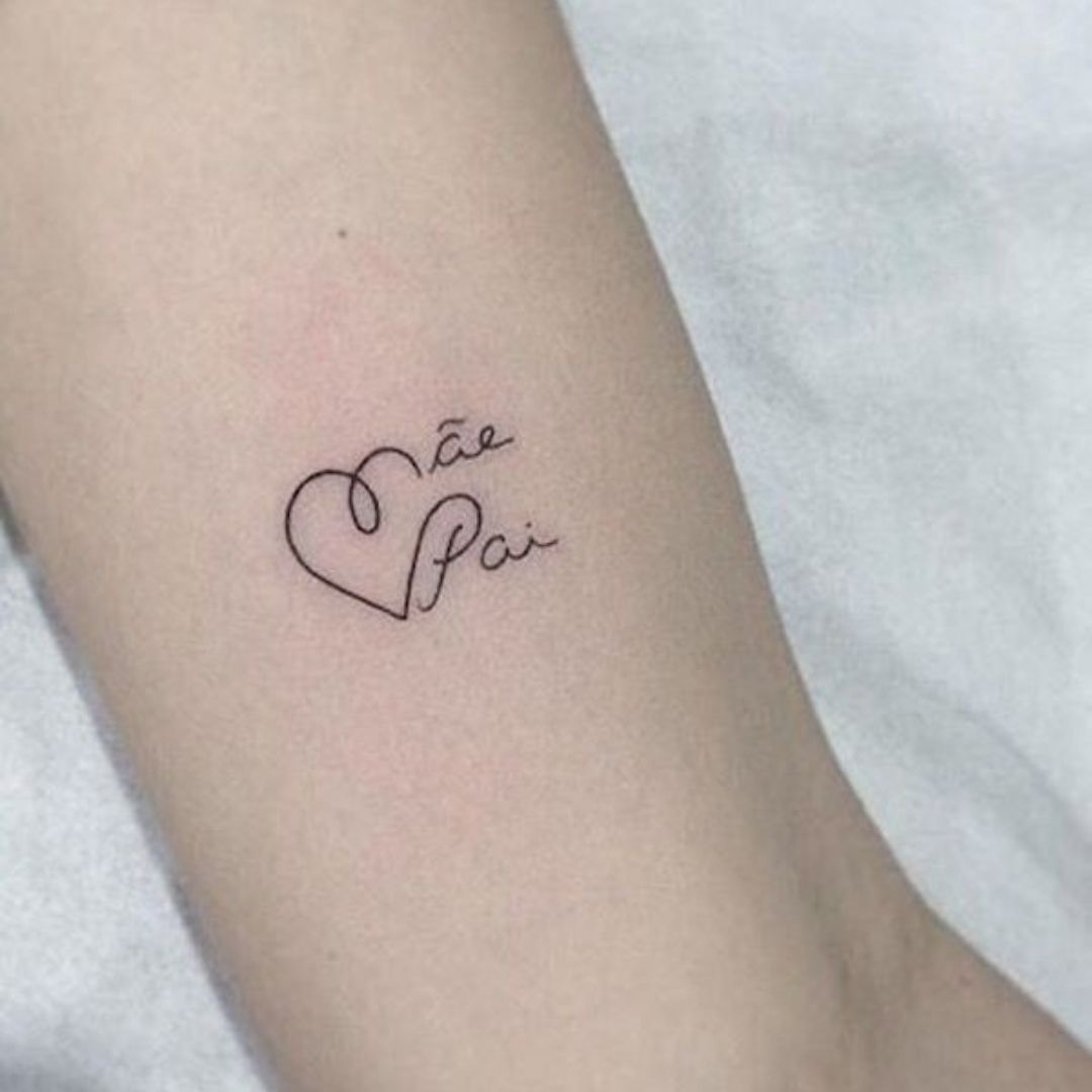 Tatuagem de coração com o nome pai e mãe em um braço feminino
