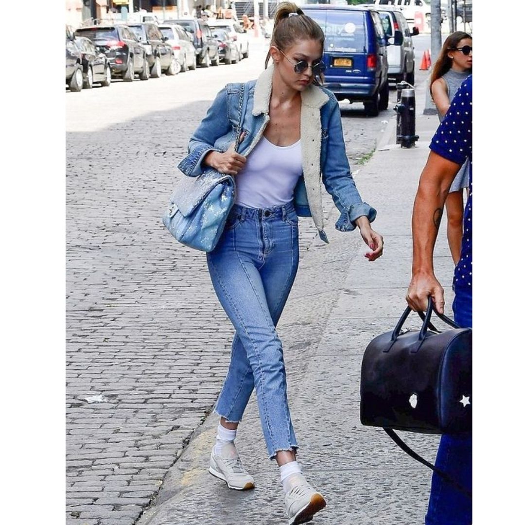 Mulher andando na rua com look com tênis e total jeans