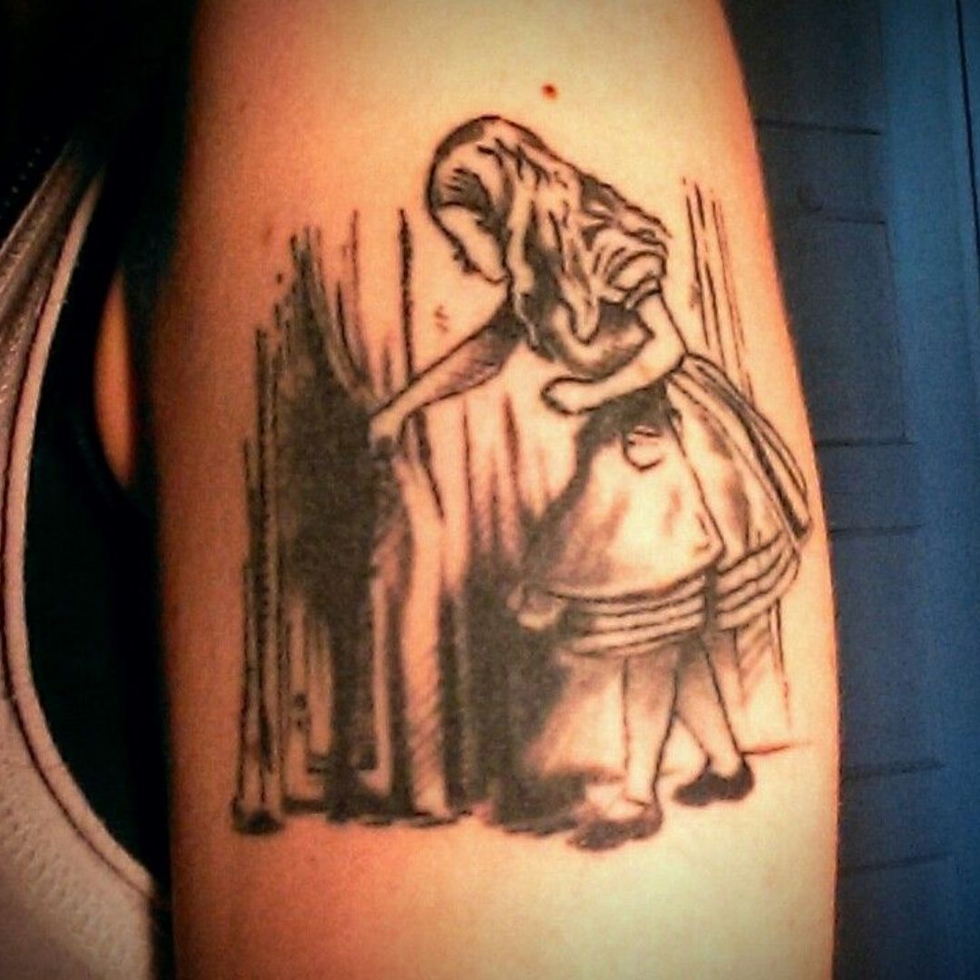 Tatuagem no braço de Alice nos pais das maravilha