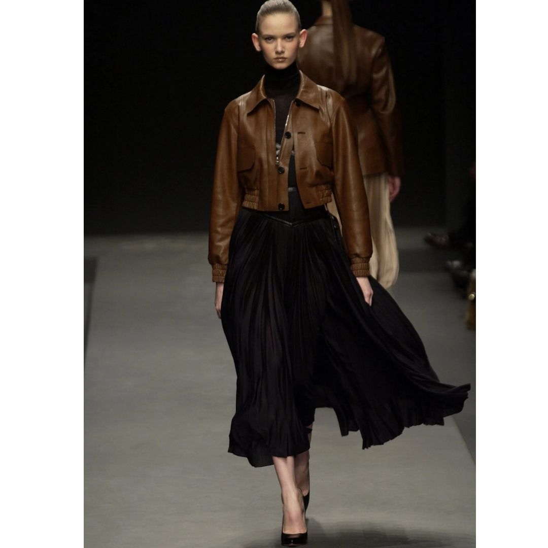 modelo desfilando  com um no vestido na preto e uma jaqueta na cor marrom café cores do inverno