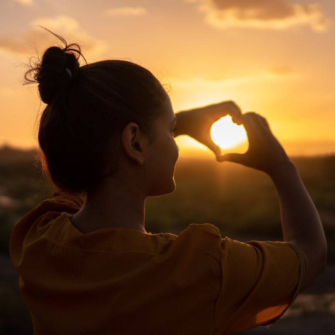 Mulher de costa fazendo coração no sol com as mãos Poses Para Fotos