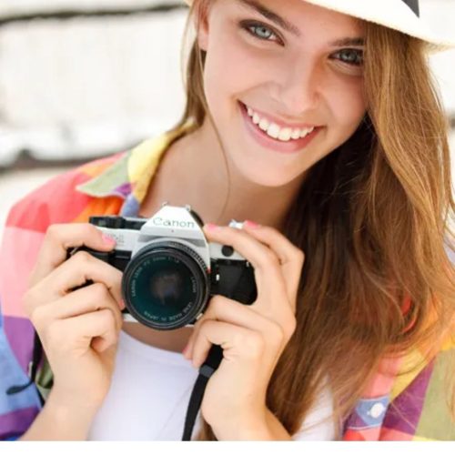 Mulher segurando uma câmera e sorrindo