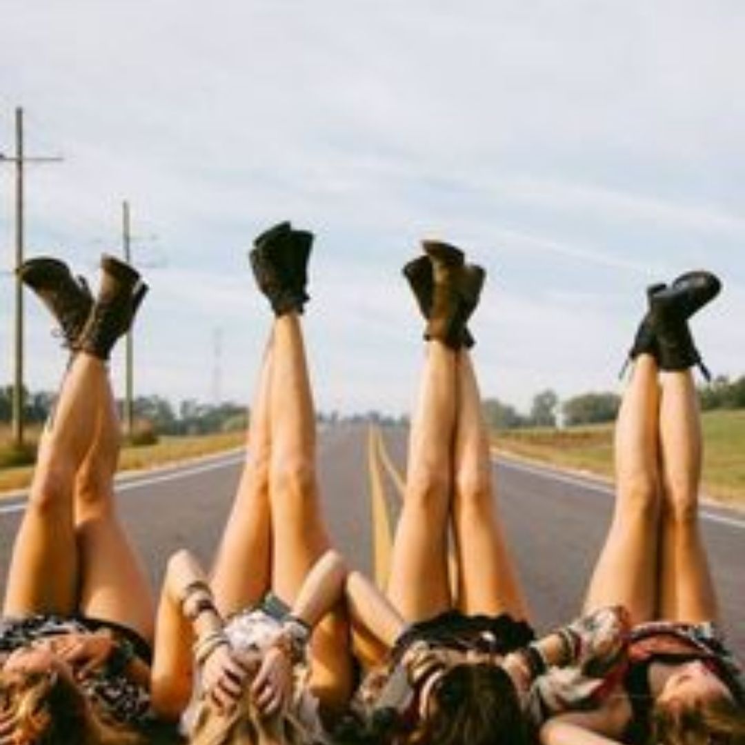 Varias mulheres deitadas na estrada com as pernas para cima 