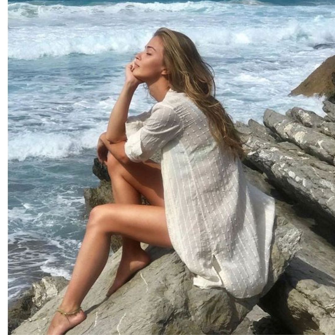 Mulher pousando para fotos na praia usando dicas de Poses Para Fotos Perfeitas