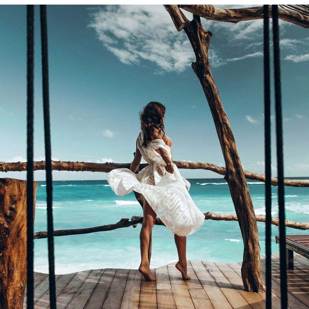 Mulher vestido de branco frente para a praia