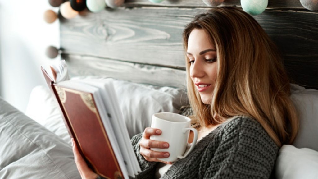 Mulher lendo um livro com um axicara na mão usando dicas de Poses Para Fotos Perfeitas