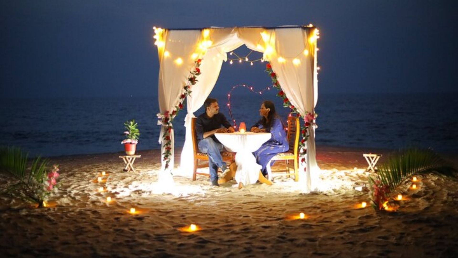Casal jantando a luz de velas em uma praia 