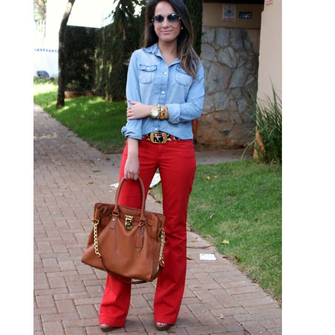 Mulher com look de trabalho composto por uma camisa jeans e uma calça vermelha