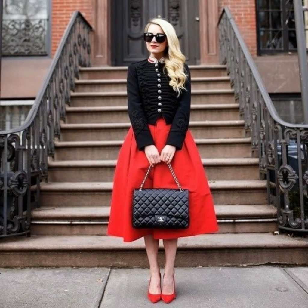 Mulher em frente a uma escadaria vestindo um look de inverno vermelho e scarpin