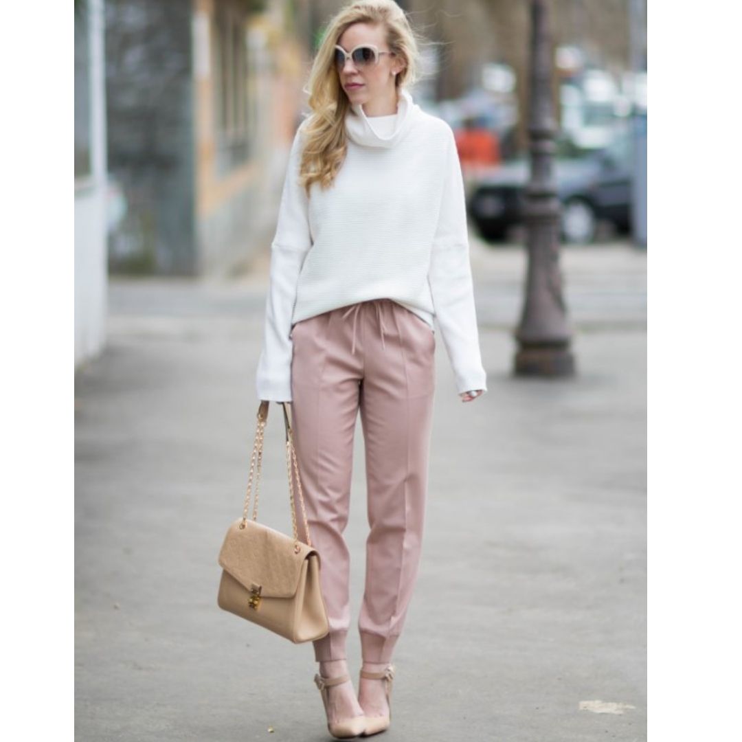 Mulher andando na rua comum look composto por uma calça rosé e uma blusa blaca
