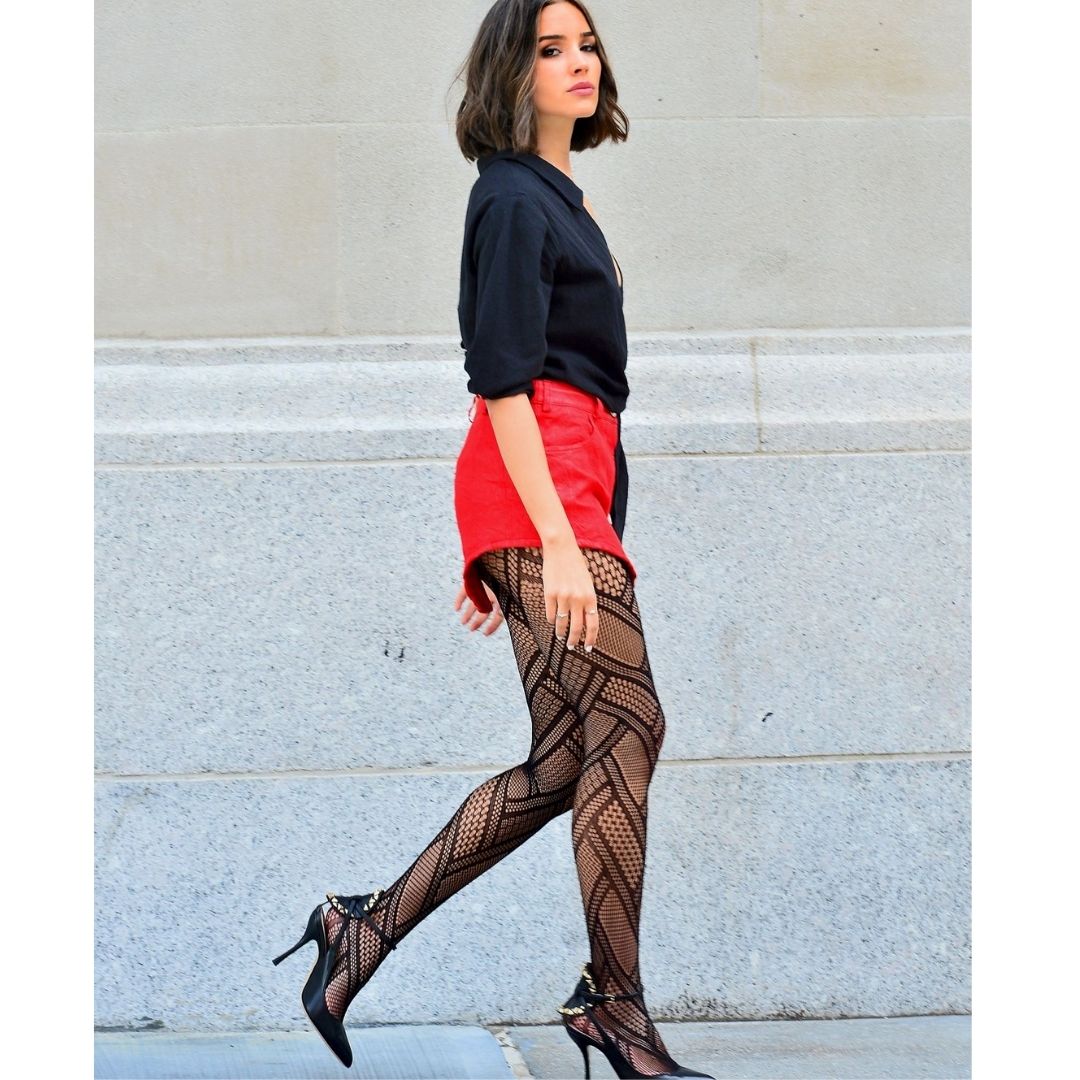 Mulher andando na rua com saia vermelha camisa preta e meias-calças e scarpin