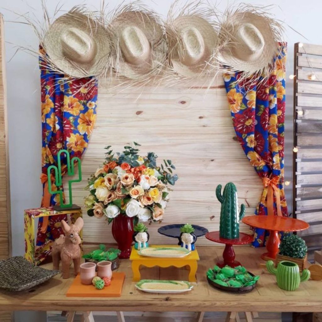 Mesa decorada com tema de festas juninas, chapéus, doces