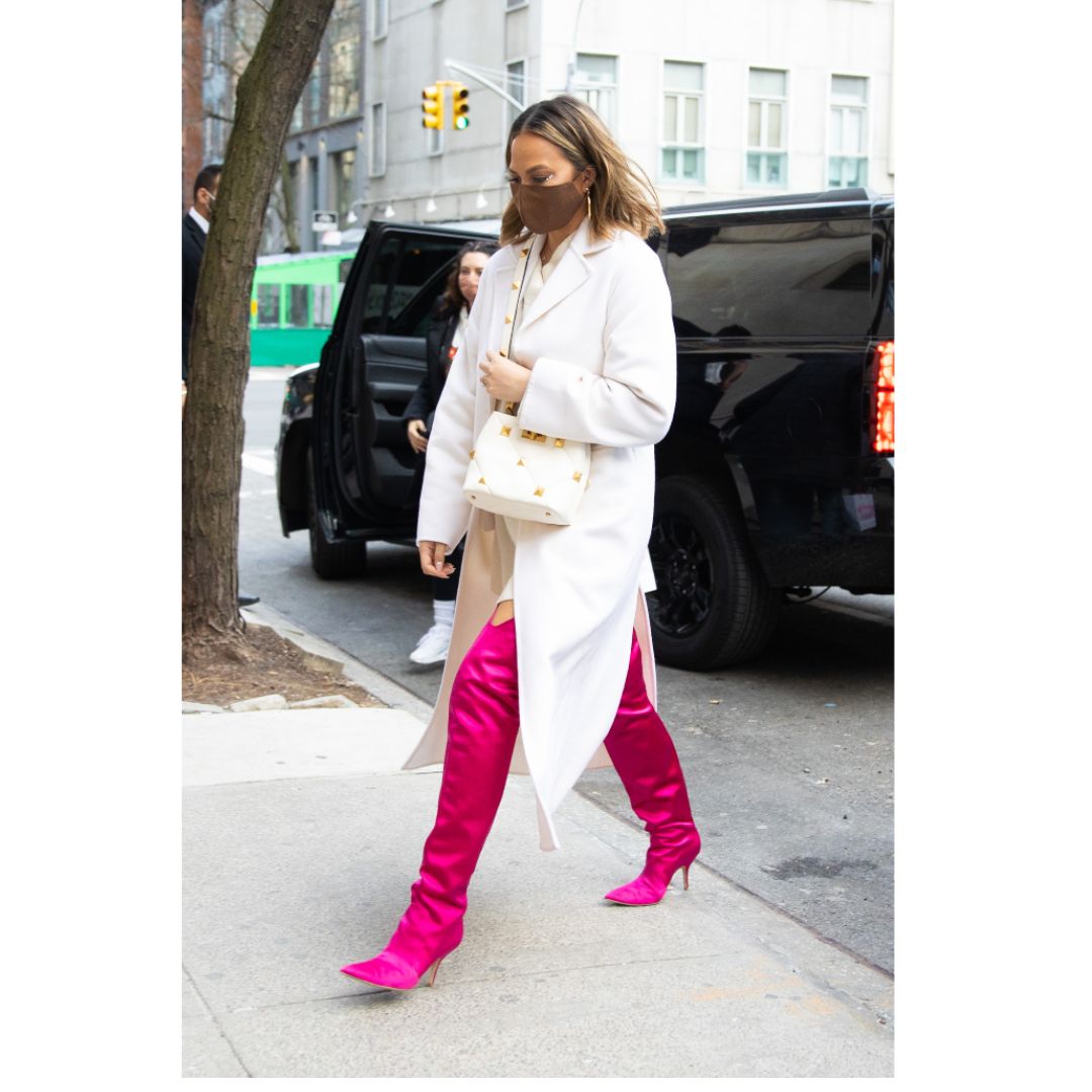 Mulher com um look de inverno na cor branco e botas cano longo na cor rosa pink