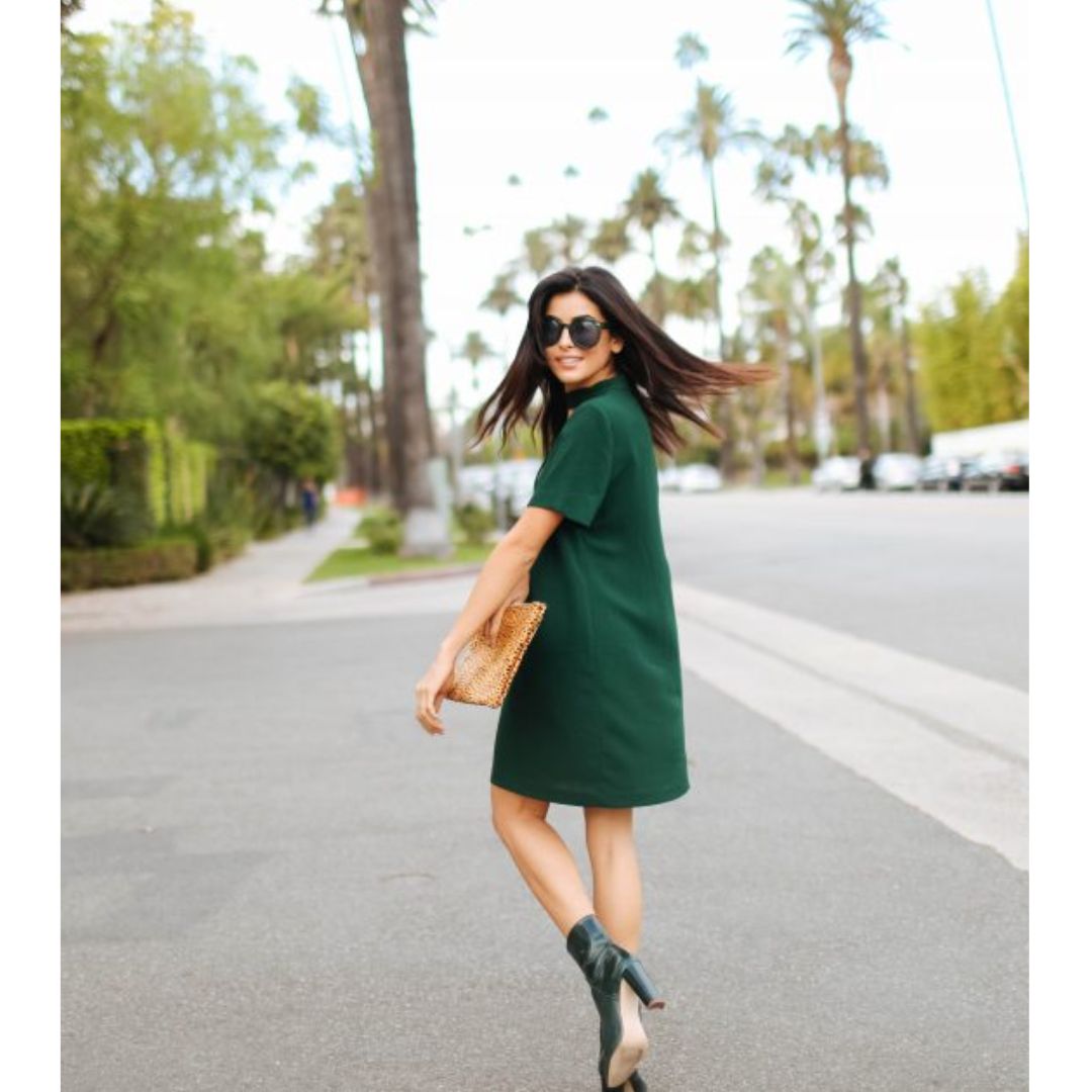 Mulher andando na rua com vestido e botas verde