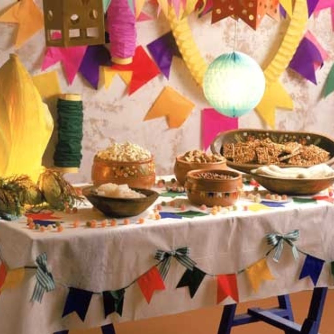 Mesa decoradas com bandeirinhas, balões e doces, para festa juninas