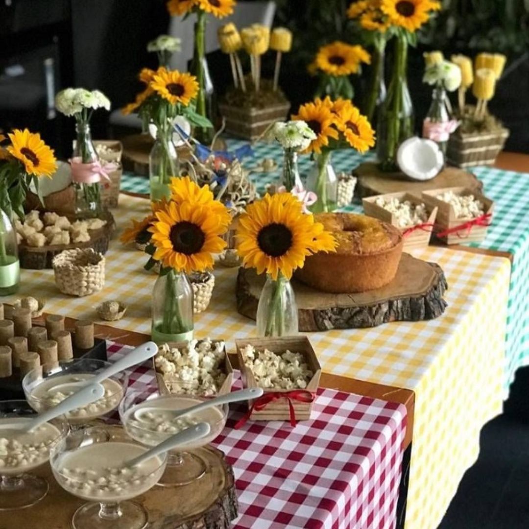 Mesa decorada com flores e xadrez para festas juninas