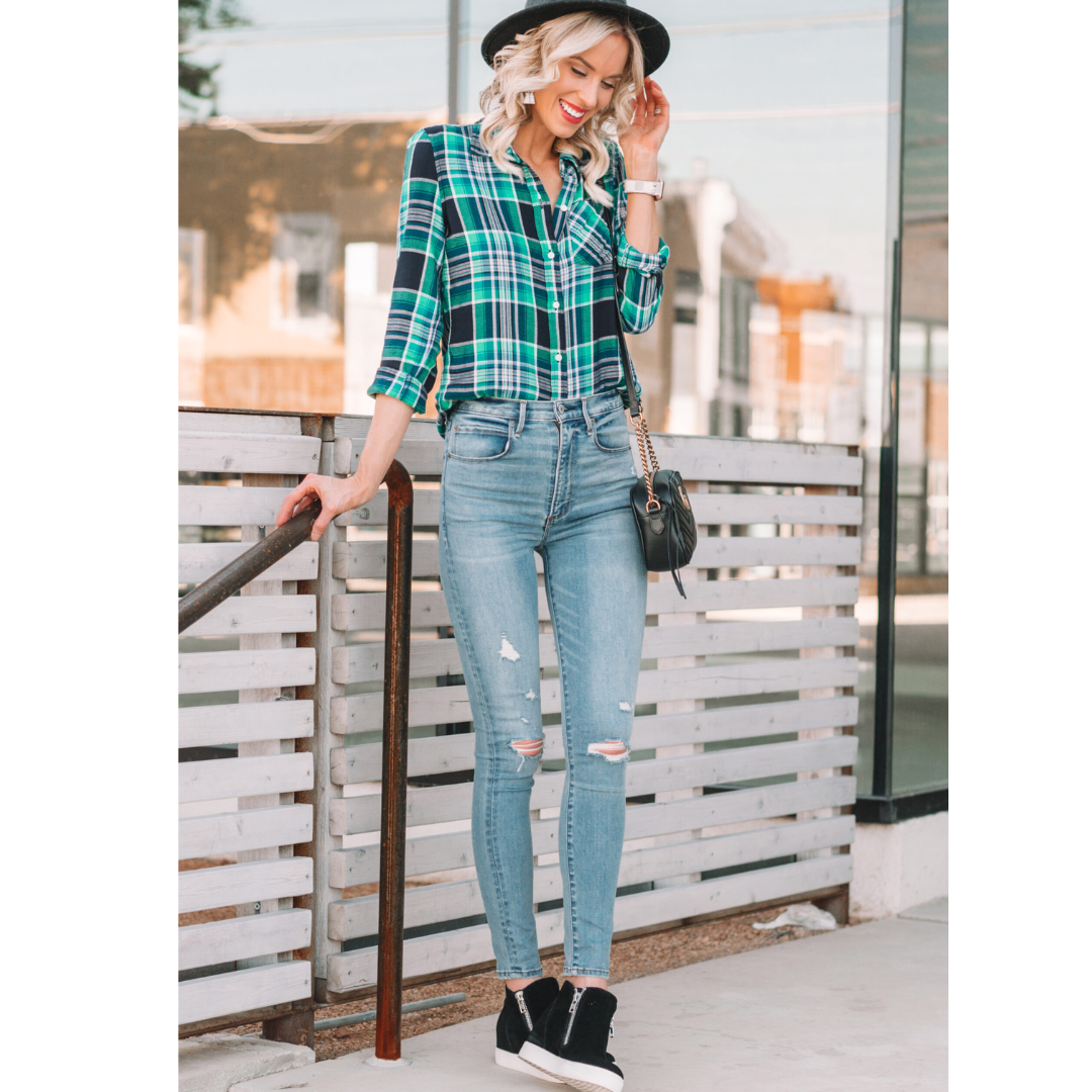 Mulher usando tênis preto, calça jeans e camisa xadrez verde