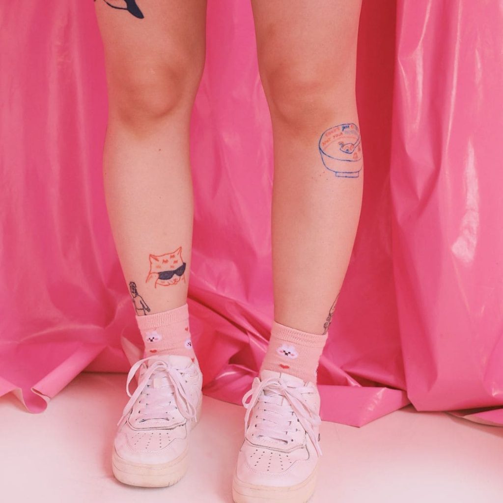 pernas tatuadas em fundo rosa