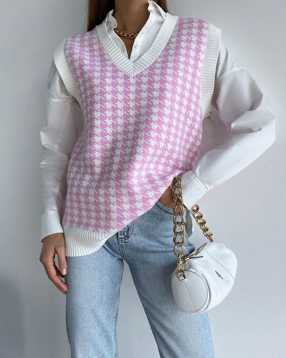 Colete de tricô xadrez rosa por cima de camisa branca e calça jeans