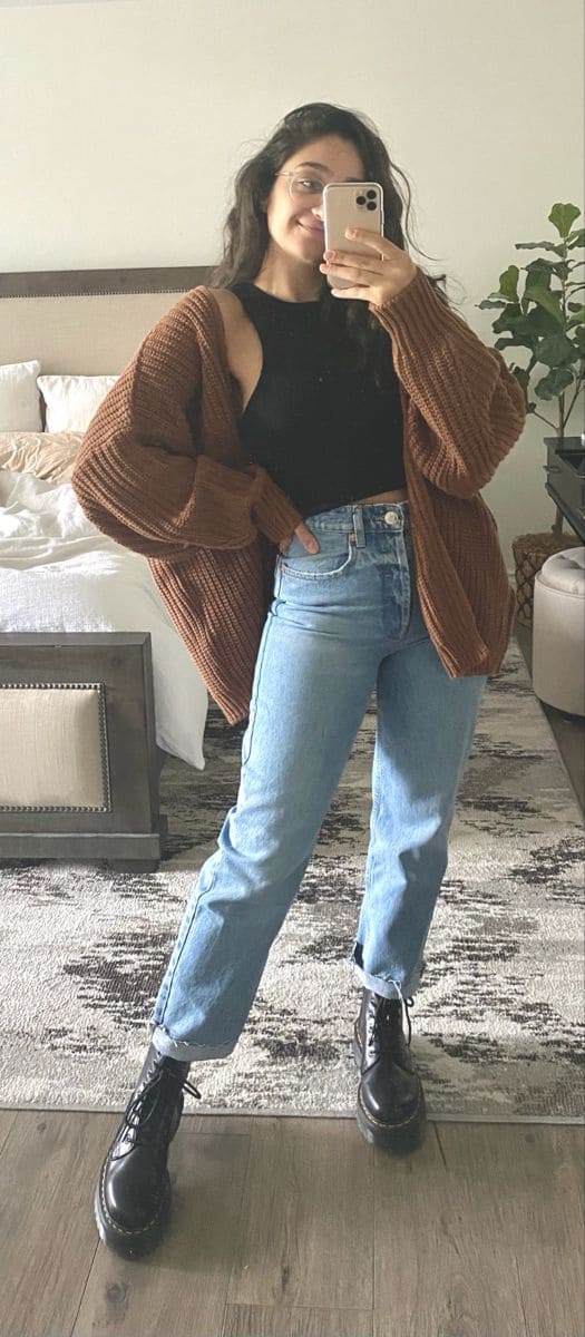 Look com calça mom jeans com barro dobrada, coturno, e sobreposição de cardigan marrom.