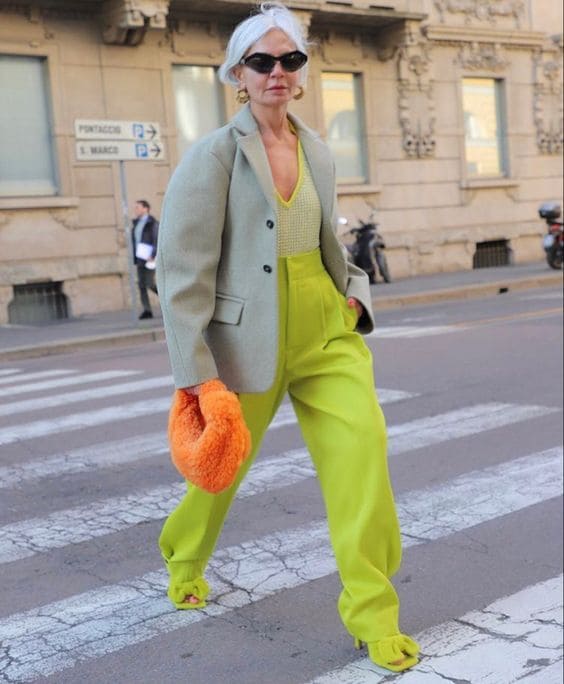 Look criativo com calça verde e bolsa laranja.