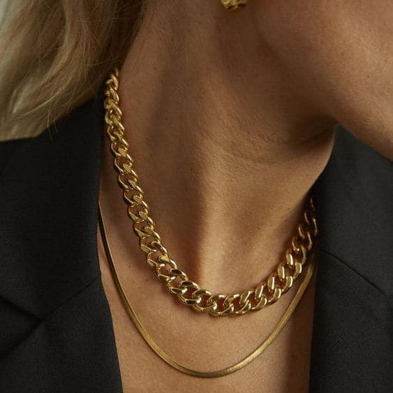 Mulher usando chocker dourada de corrente e colar laminado dourado.