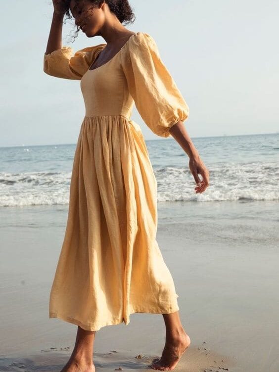 Mulher na praia com vestido amarelo