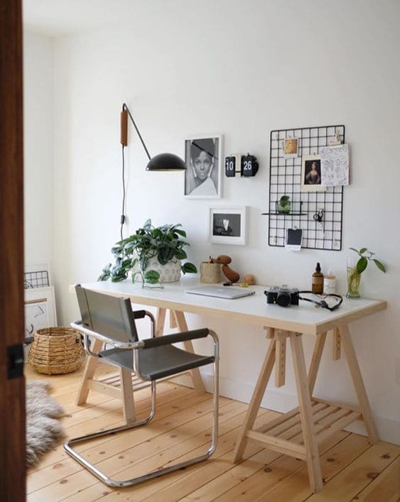 Decoração de escritório com mesa branca, cadeira preta e decorações na parede