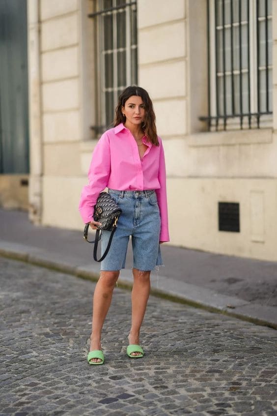 Mulher usando uma combinação de look com bermuda jeans e camisa rosa