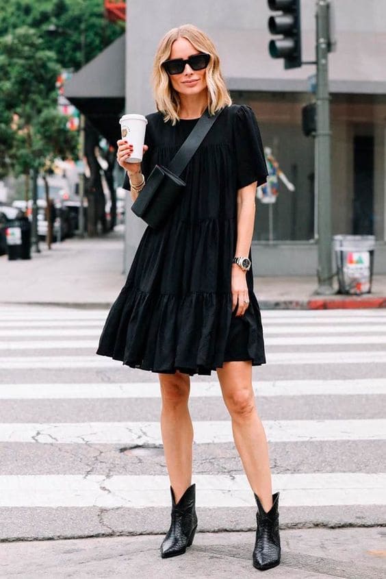 Mulher usando um look com vestido preto curto e bota