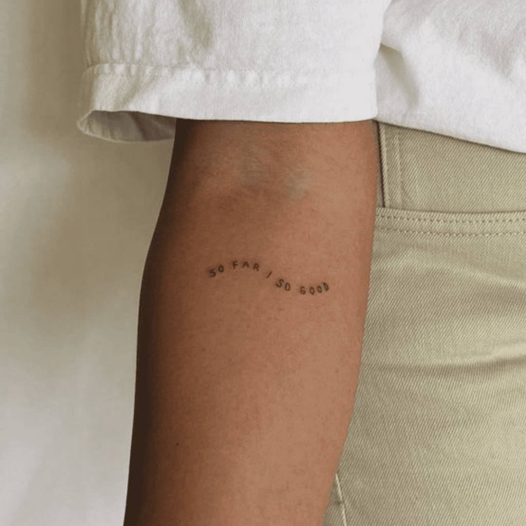 Mulher com tatuagem de frase no braço
