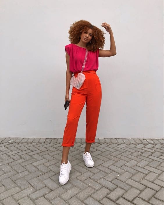 Mulher usando look de calça laranja e blusa pink