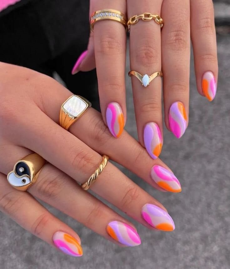 Mulher usando anéis de ouro com as unhas coloridas