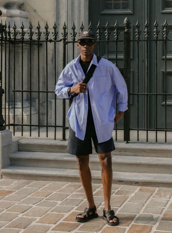 Homem usando look com sandália de couro masculina, camisa listrada e bermuda.