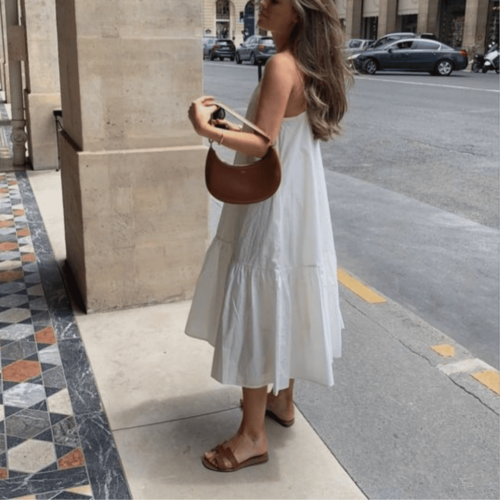 Mulher usando vestido branco, bolsa marrom e sandália para o verão