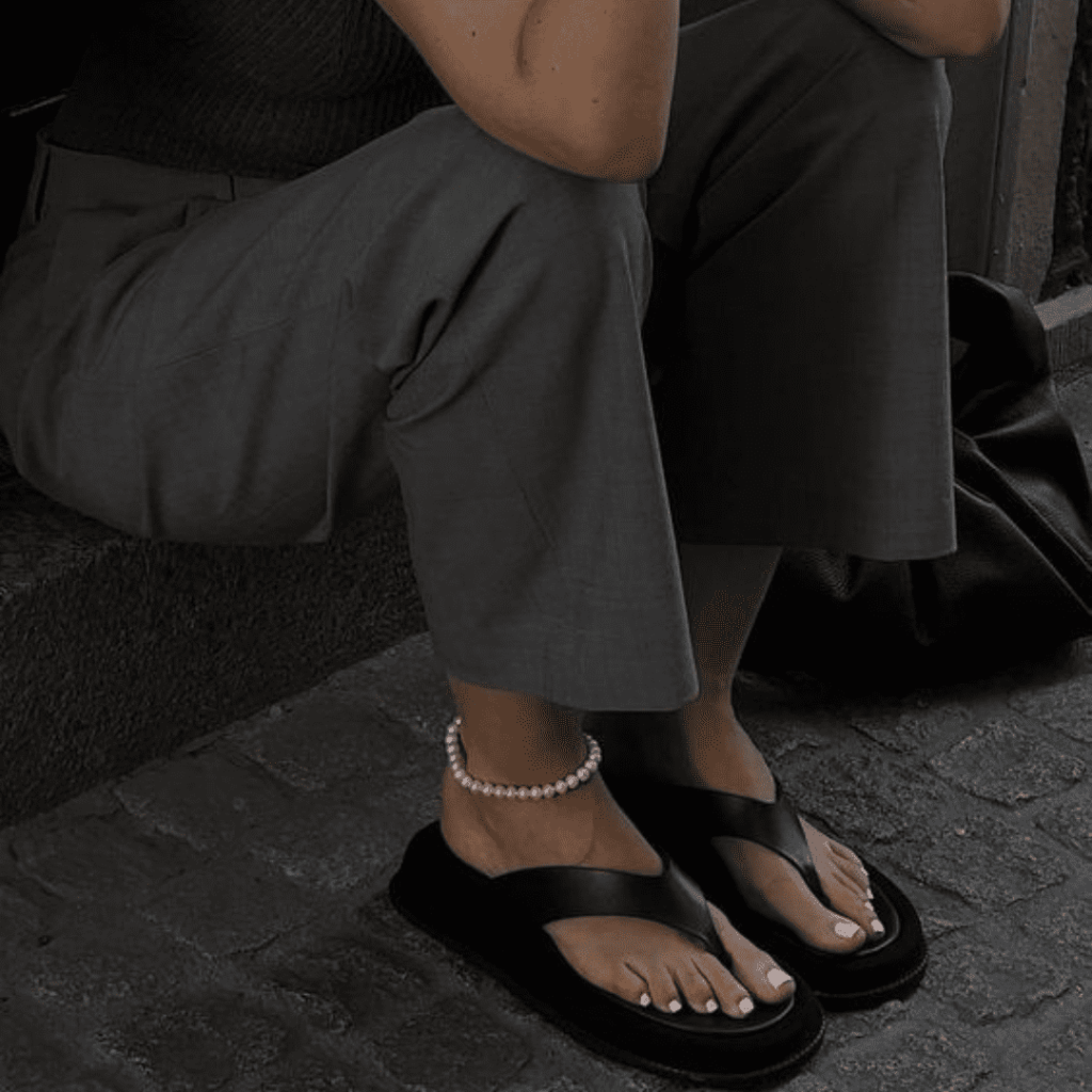 Mulher sentada usando um chinelo da moda 2024