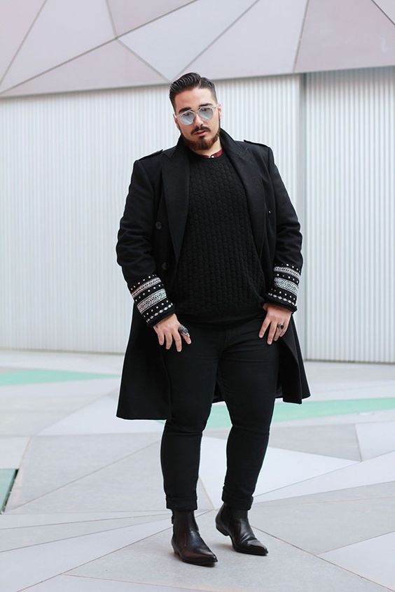 Homem usando um outfit all-black, óculos escuros e um tipo de sapato masculino parecido com uma bota western