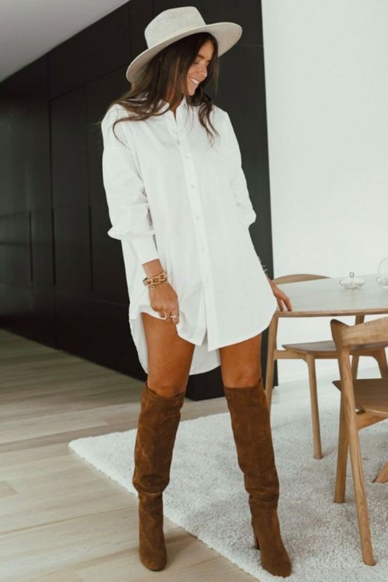 Mulher usando uma roupa que combina com bota composta por camisa branca e bota de cano longo de cor marrom