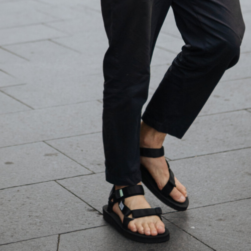 Pernas de um homem mostrando como usar chinelo masculino preto estilo papete